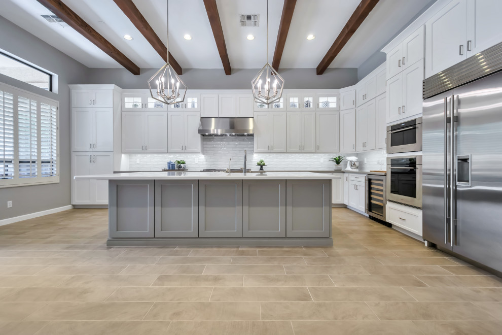 Eat-in kitchen - large transitional l-shaped porcelain tile and brown floor eat-in kitchen idea in Phoenix with a farmhouse sink, shaker cabinets, white cabinets, quartz countertops, white backsplash, subway tile backsplash, stainless steel appliances, an island and gray countertops