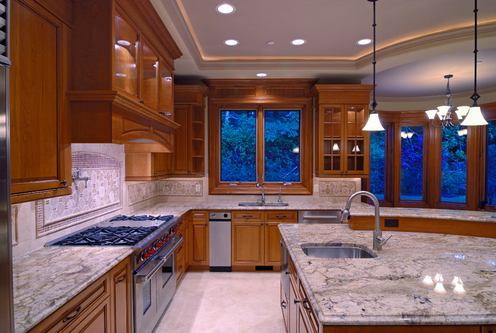 Large transitional l-shaped travertine floor kitchen photo in Phoenix with raised-panel cabinets, medium tone wood cabinets, granite countertops, beige backsplash, ceramic backsplash, stainless steel appliances, an island and an undermount sink