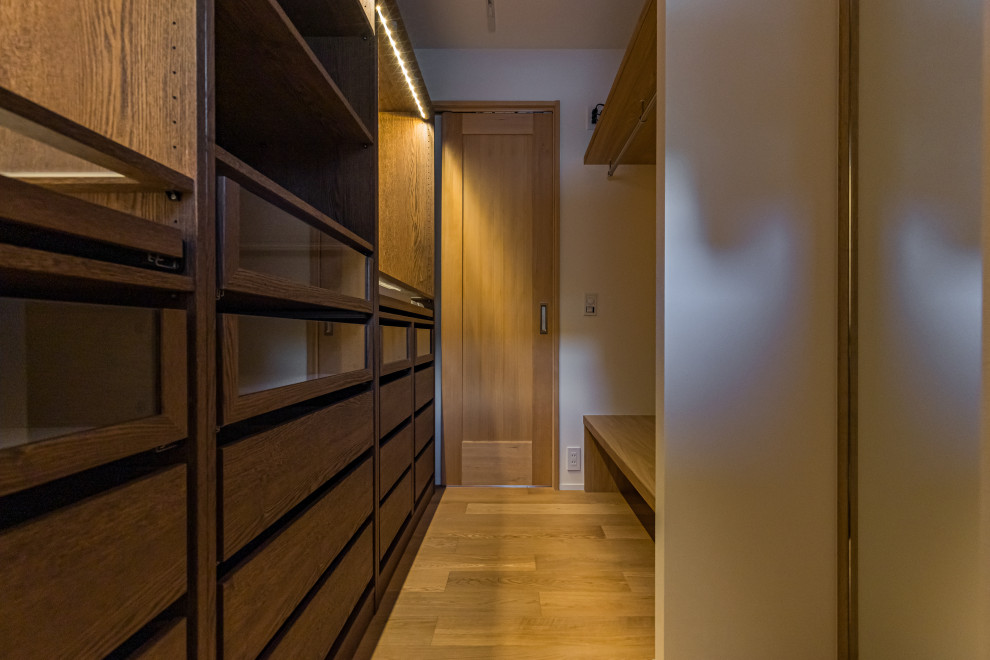 Réalisation d'un dressing room minimaliste de taille moyenne et neutre avec un sol en bois brun, un sol marron et un plafond en papier peint.