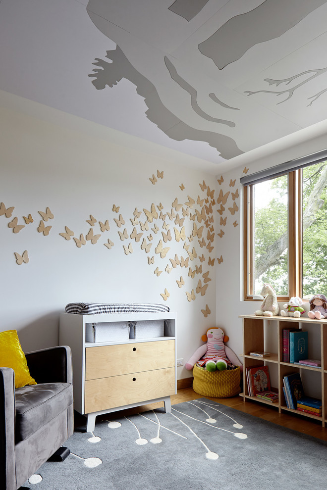 Example of a trendy girl light wood floor and brown floor nursery design in Kansas City with white walls