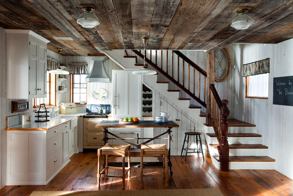 Photo of a country l-shaped kitchen in Boston with a farmhouse sink, flat-panel cabinets, white cabinets, medium hardwood floors and with island.