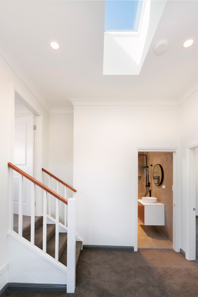 This is an example of a mid-sized modern hallway in Sydney with white walls, carpet and brown floor.