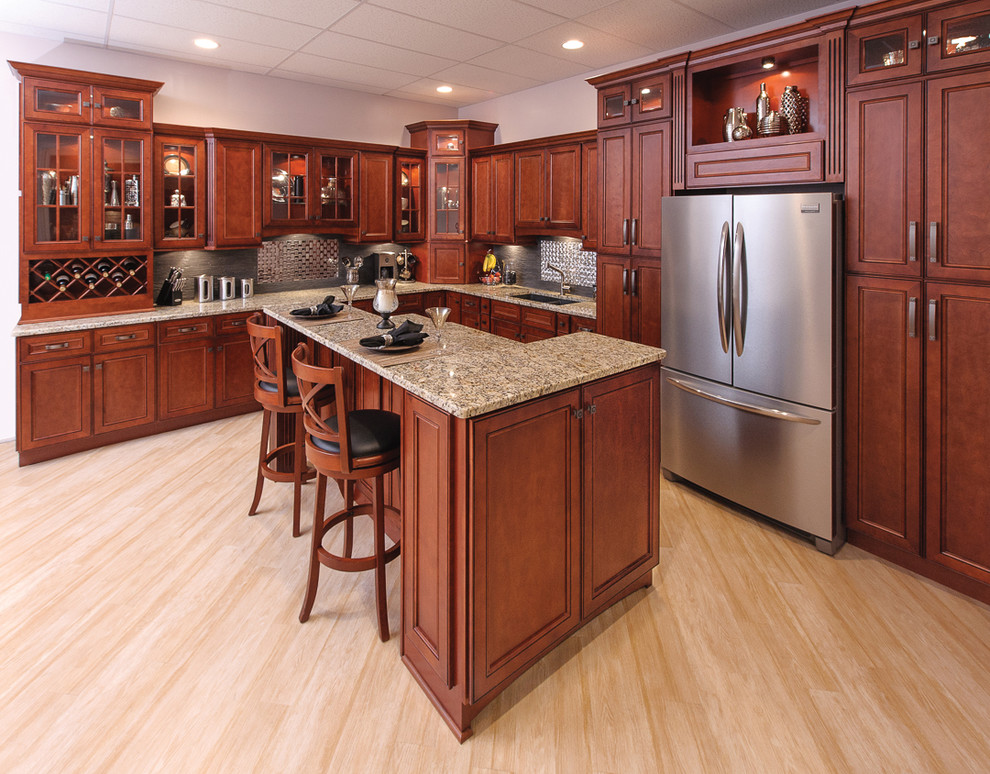 Large transitional l-shaped laminate floor and beige floor enclosed kitchen photo in Orange County with an undermount sink, beaded inset cabinets, medium tone wood cabinets, granite countertops, beige backsplash, stone tile backsplash, stainless steel appliances and no island