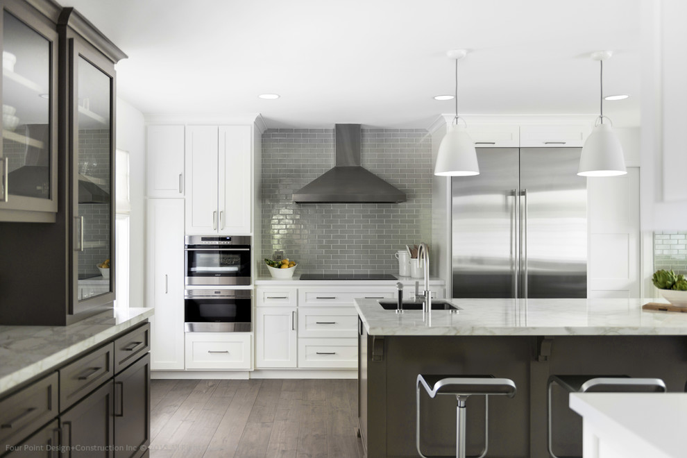 Design ideas for a large transitional u-shaped kitchen pantry in Los Angeles with a farmhouse sink, shaker cabinets, white cabinets, solid surface benchtops, green splashback, subway tile splashback, stainless steel appliances, medium hardwood floors and with island.