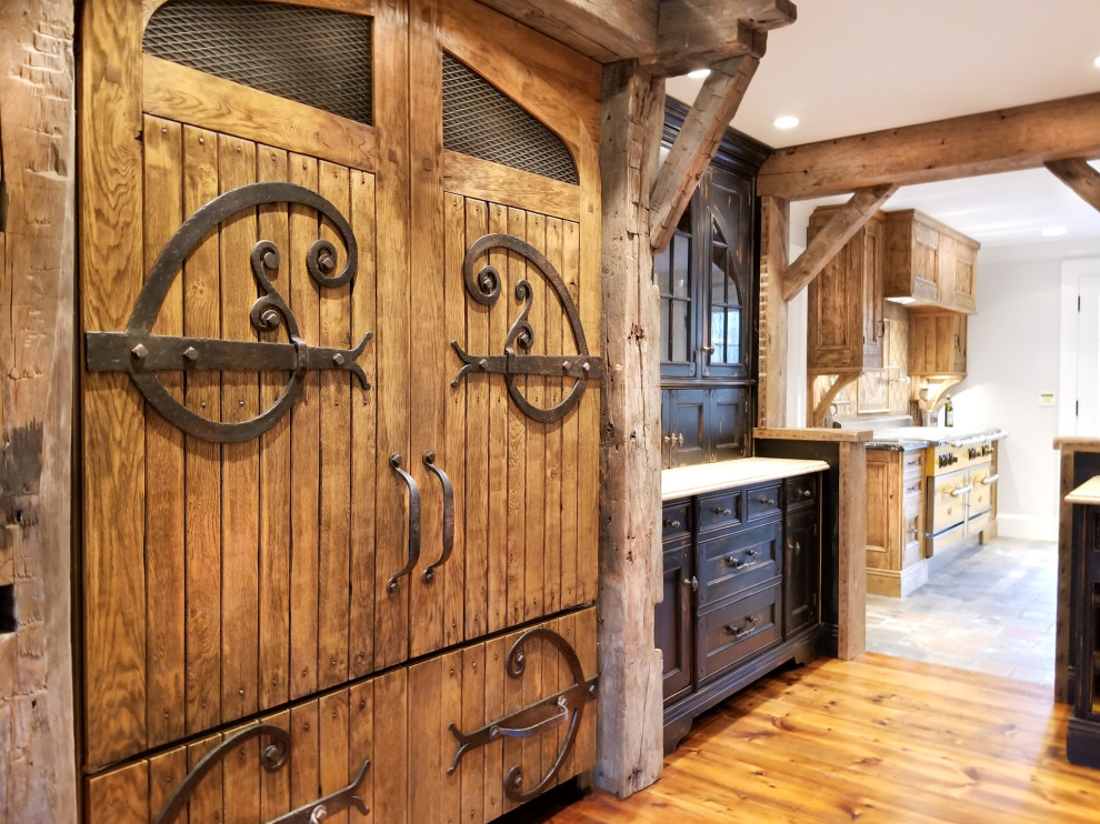 Ispirazione per una grande cucina lineare rustica chiusa con ante con bugna sagomata, ante nere, pavimento in legno massello medio e top bianco