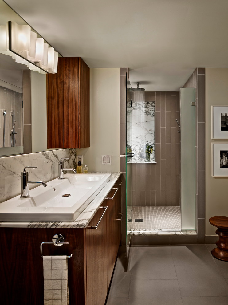 This is an example of a large contemporary master bathroom in Philadelphia with a trough sink, flat-panel cabinets, dark wood cabinets, an alcove shower, gray tile, beige walls, a two-piece toilet, cement tiles, marble benchtops, grey floor and a hinged shower door.
