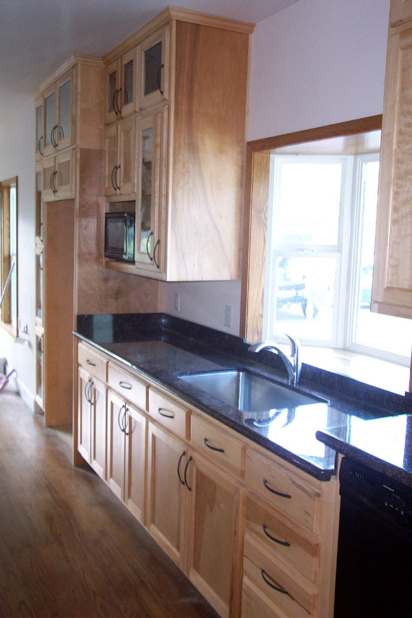 Photo of a kitchen in Other with shaker cabinets, light wood cabinets, black appliances and with island.