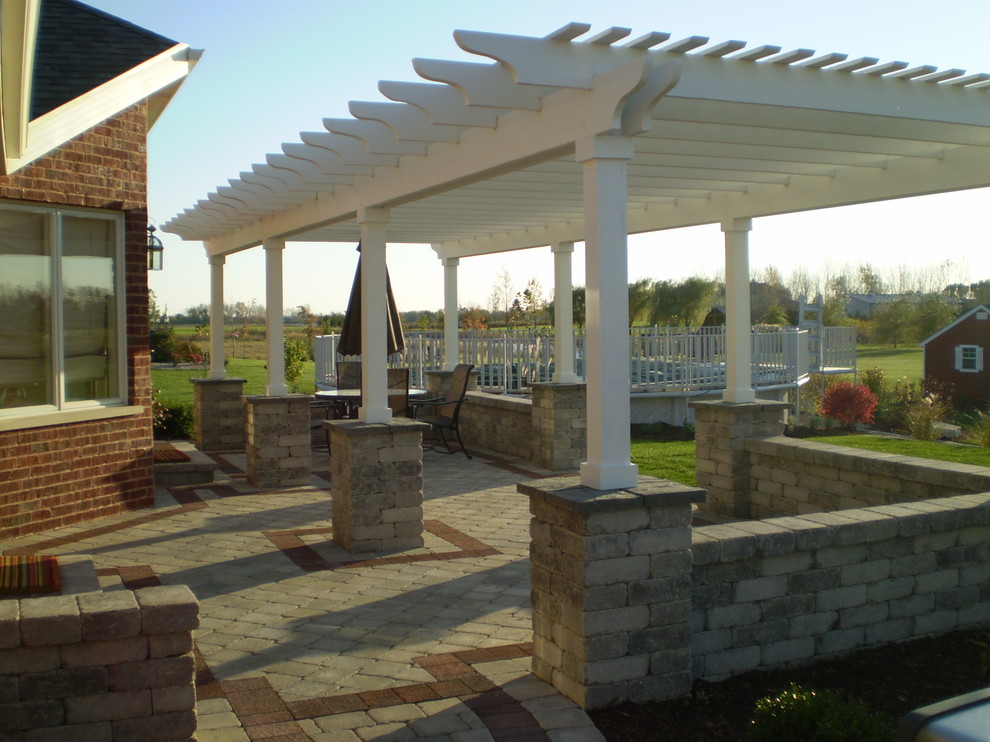 Design ideas for a mid-sized traditional backyard patio in Chicago with brick pavers and a pergola.