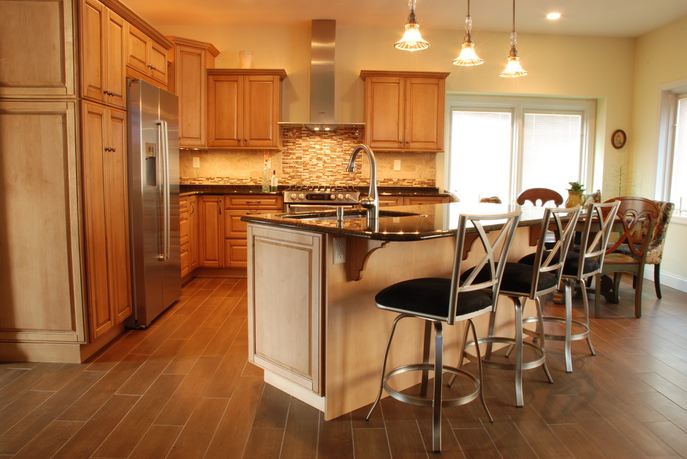 Eat-in kitchen - mid-sized transitional l-shaped ceramic tile eat-in kitchen idea with a farmhouse sink, raised-panel cabinets, medium tone wood cabinets, granite countertops, beige backsplash, ceramic backsplash, stainless steel appliances and an island
