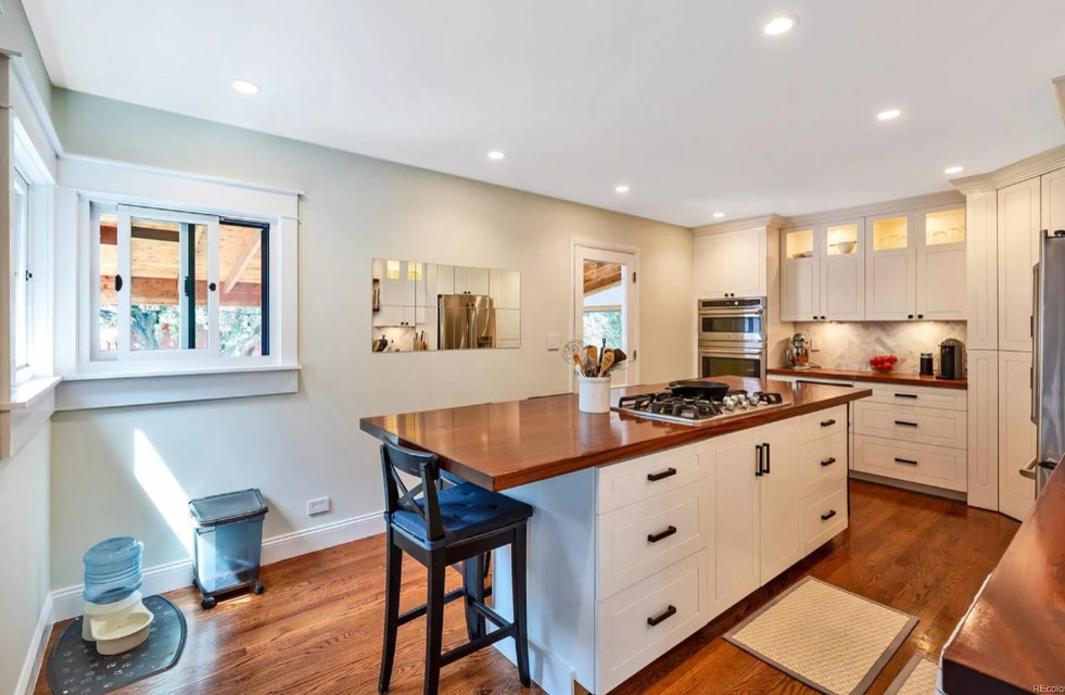 Mid-sized transitional u-shaped dark wood floor and brown floor eat-in kitchen photo in Denver with an undermount sink, recessed-panel cabinets, white cabinets, wood countertops, white backsplash, marble backsplash, stainless steel appliances, an island and brown countertops