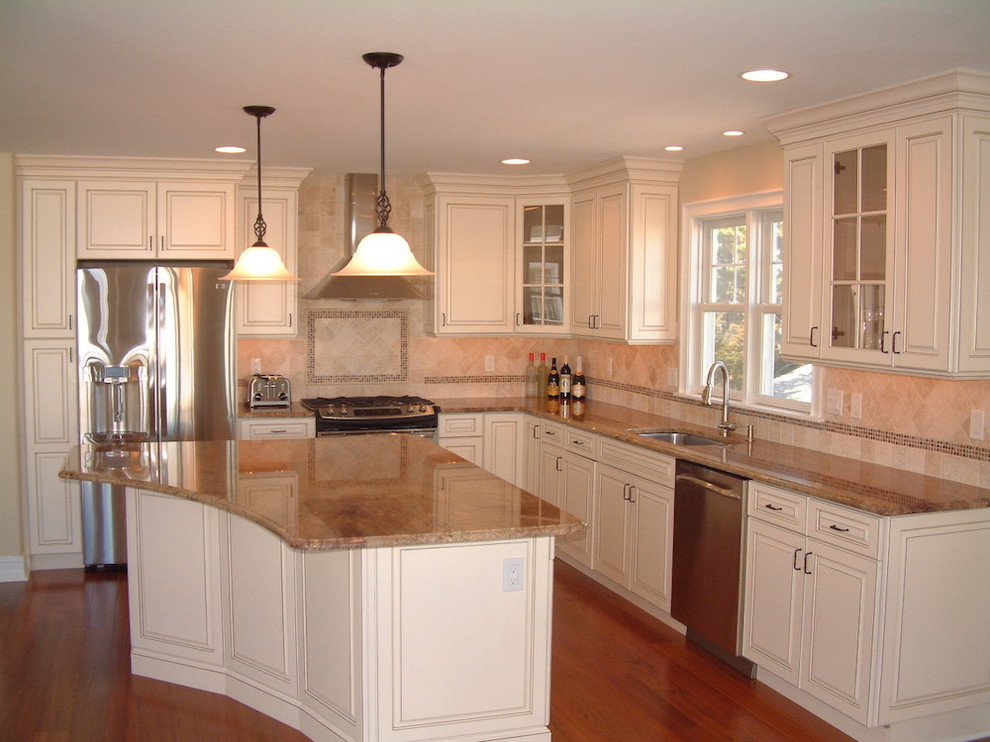 Medium tone wood floor kitchen photo in Philadelphia with a drop-in sink, white cabinets, granite countertops, white backsplash, stainless steel appliances and an island