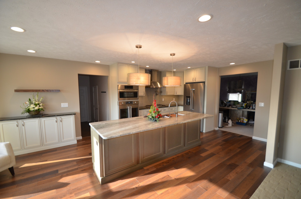 Example of a mid-sized transitional u-shaped medium tone wood floor and brown floor eat-in kitchen design with an undermount sink, raised-panel cabinets, beige cabinets, granite countertops, multicolored backsplash, mosaic tile backsplash, stainless steel appliances, an island and multicolored countertops