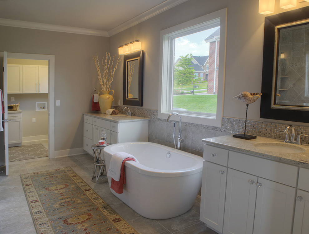 Large transitional master gray tile and ceramic tile ceramic tile freestanding bathtub photo with an undermount sink, shaker cabinets, white cabinets, granite countertops, a one-piece toilet and gray walls