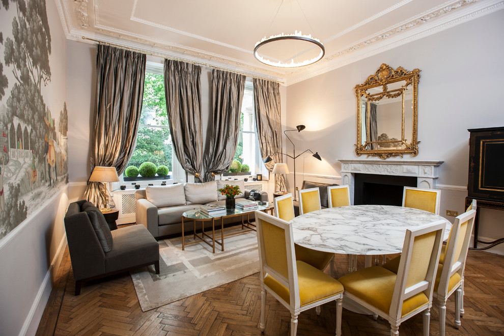 Traditional open plan dining in London with grey walls, a standard fireplace and medium hardwood floors.