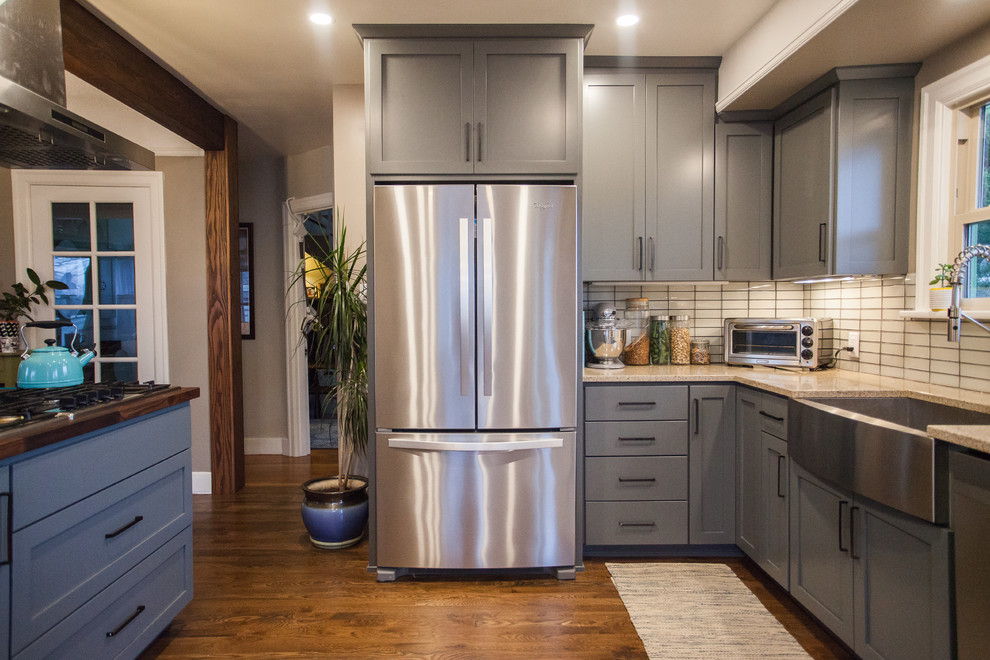 Open concept kitchen - small transitional l-shaped dark wood floor and brown floor open concept kitchen idea in Seattle with a farmhouse sink, shaker cabinets, gray cabinets, stainless steel appliances, an island, granite countertops, white backsplash, porcelain backsplash and beige countertops