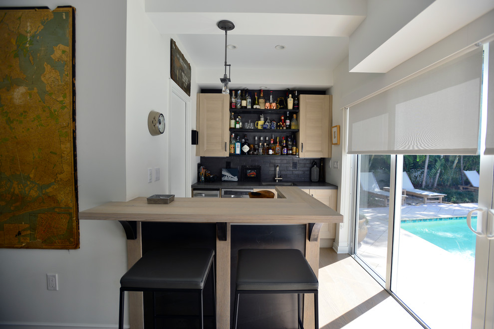Photo of a small contemporary single-wall wet bar in Miami with an undermount sink, shaker cabinets, light wood cabinets, wood benchtops, black splashback, subway tile splashback and beige floor.