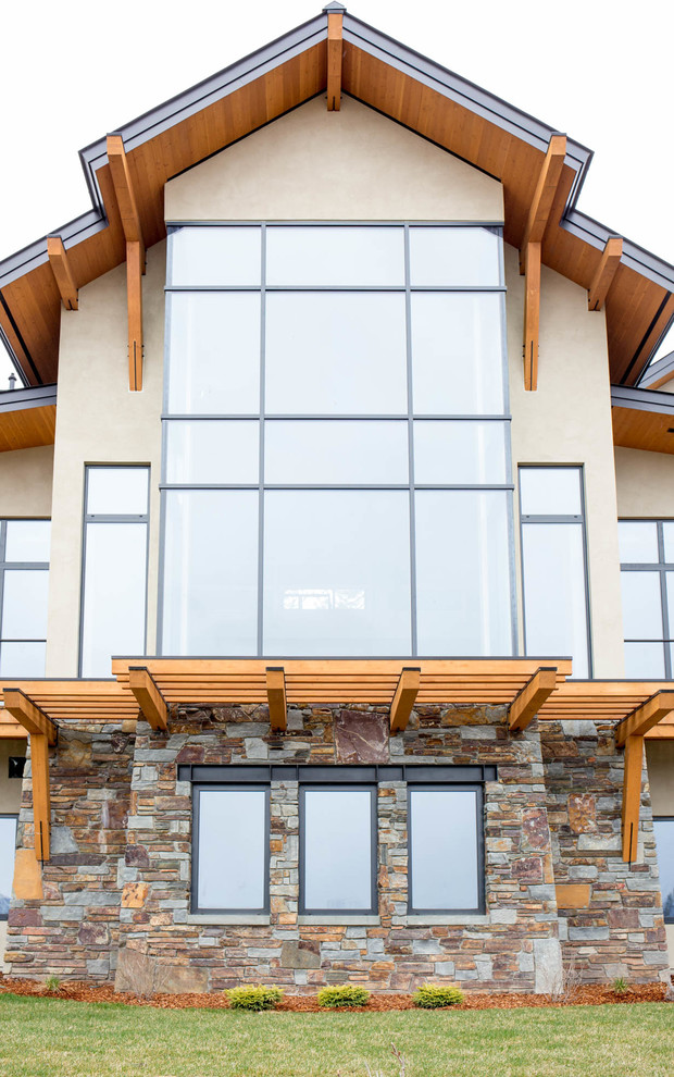 Large rustic beige three-story stucco gable roof idea