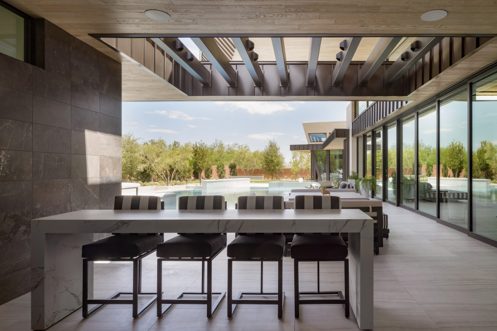 Expansive contemporary back patio in Las Vegas with an outdoor kitchen, tiled flooring and a roof extension.