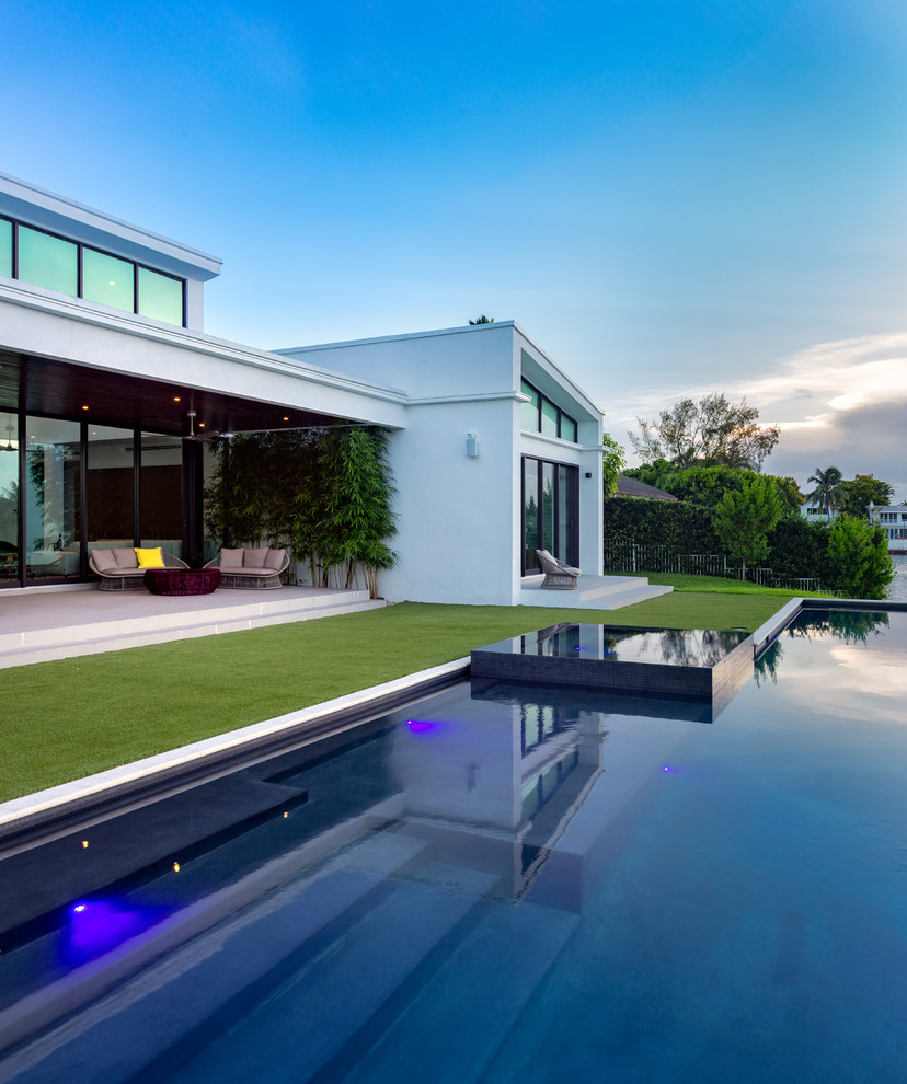 Design ideas for a contemporary backyard custom-shaped lap pool in Miami with a hot tub.