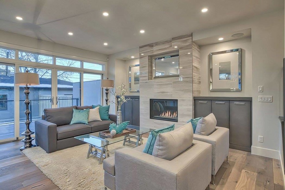 Large contemporary living room in Calgary with grey walls, medium hardwood floors, a standard fireplace and a stone fireplace surround.