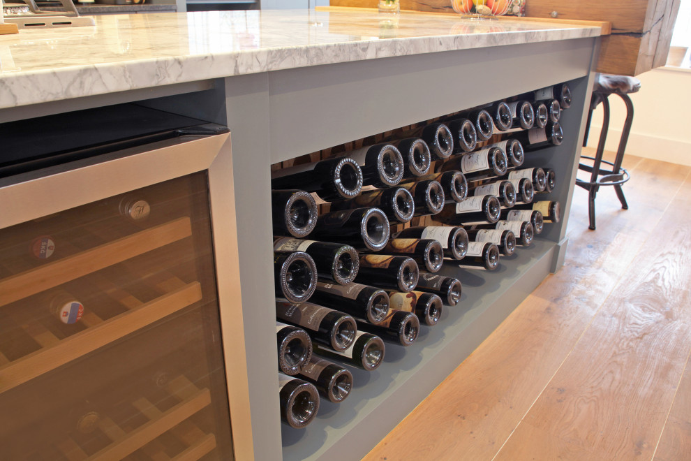 Transitional wine cellar in London with light hardwood floors, display racks and beige floor.