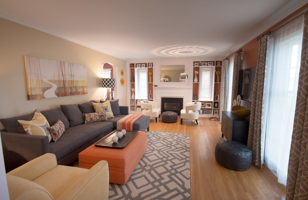 Photo of a large contemporary enclosed living room in Minneapolis with beige walls, light hardwood floors, a standard fireplace, a wood fireplace surround and a wall-mounted tv.