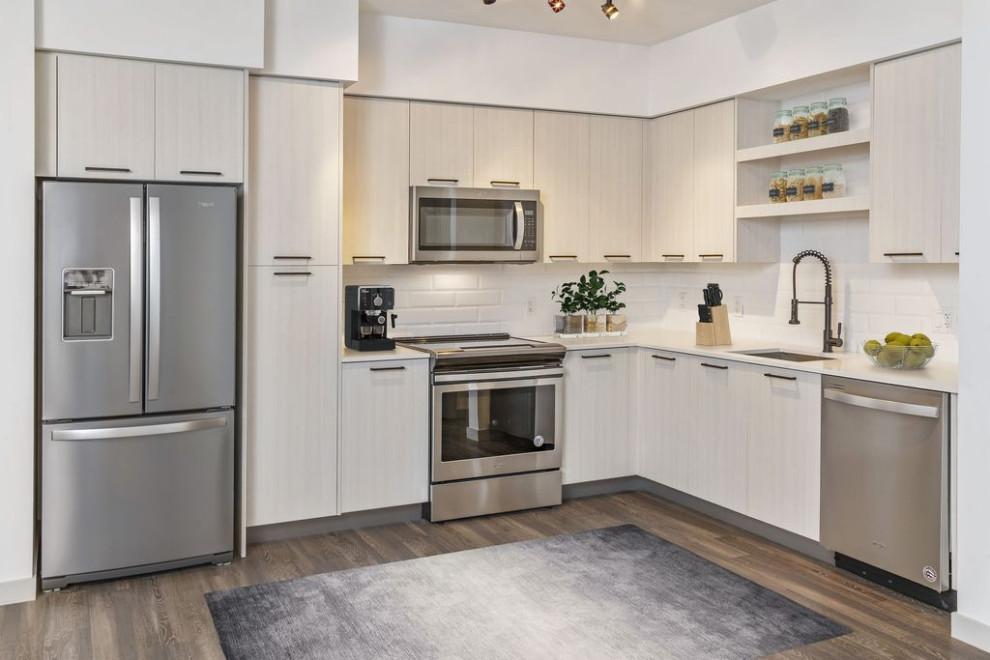 Inspiration for a small modern l-shaped kitchen in Los Angeles with a built-in sink, beige cabinets, engineered stone countertops, white splashback, metro tiled splashback, stainless steel appliances, dark hardwood flooring, no island, brown floors and beige worktops.