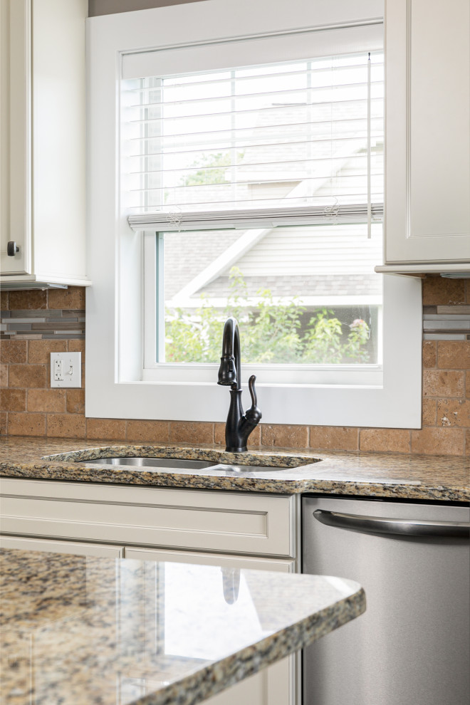 Mid-sized transitional l-shaped medium tone wood floor, brown floor and vaulted ceiling eat-in kitchen photo with an undermount sink, flat-panel cabinets, white cabinets, granite countertops, beige backsplash, stone tile backsplash, stainless steel appliances, an island and beige countertops