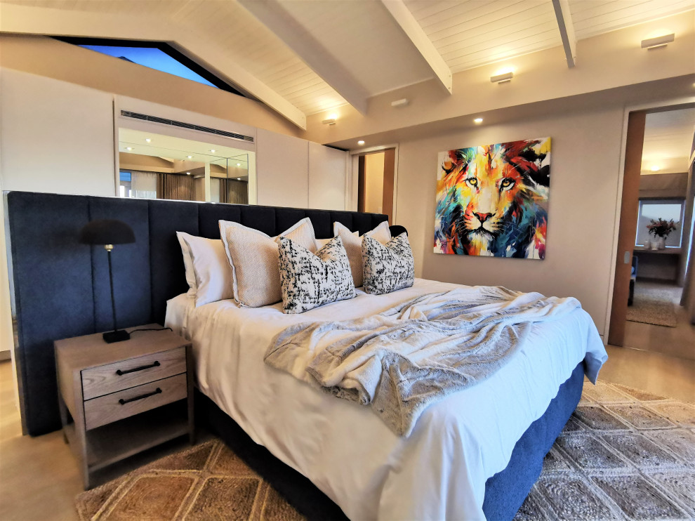 Large coastal master bedroom with white walls, no fireplace, brown floors and exposed beams.