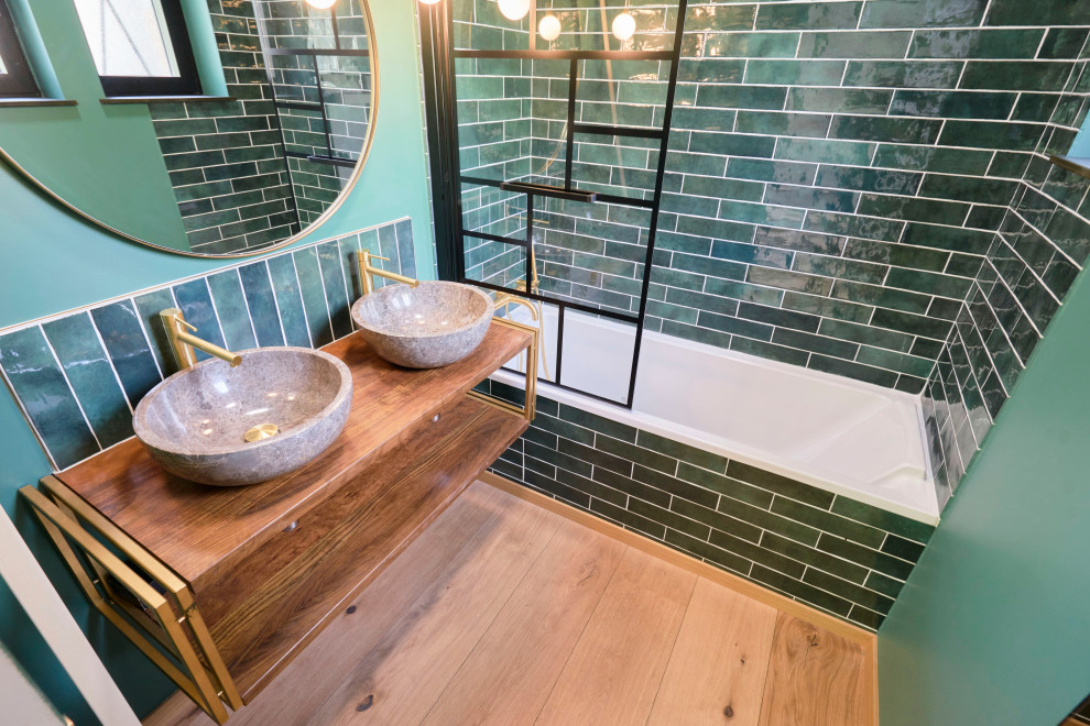 Cette photo montre une petite salle de bain éclectique avec une baignoire encastrée, un carrelage vert, des carreaux en terre cuite, un mur vert, un lavabo de ferme, un plan de toilette en bois, un sol gris, un plan de toilette blanc et meuble double vasque.