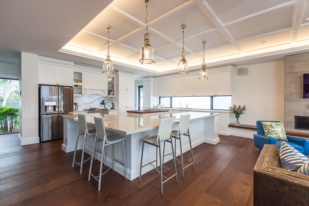 Design ideas for a large traditional open plan kitchen in Gold Coast - Tweed with an undermount sink, shaker cabinets, white cabinets, quartz benchtops, white splashback, stone slab splashback, stainless steel appliances, medium hardwood floors, with island and brown floor.
