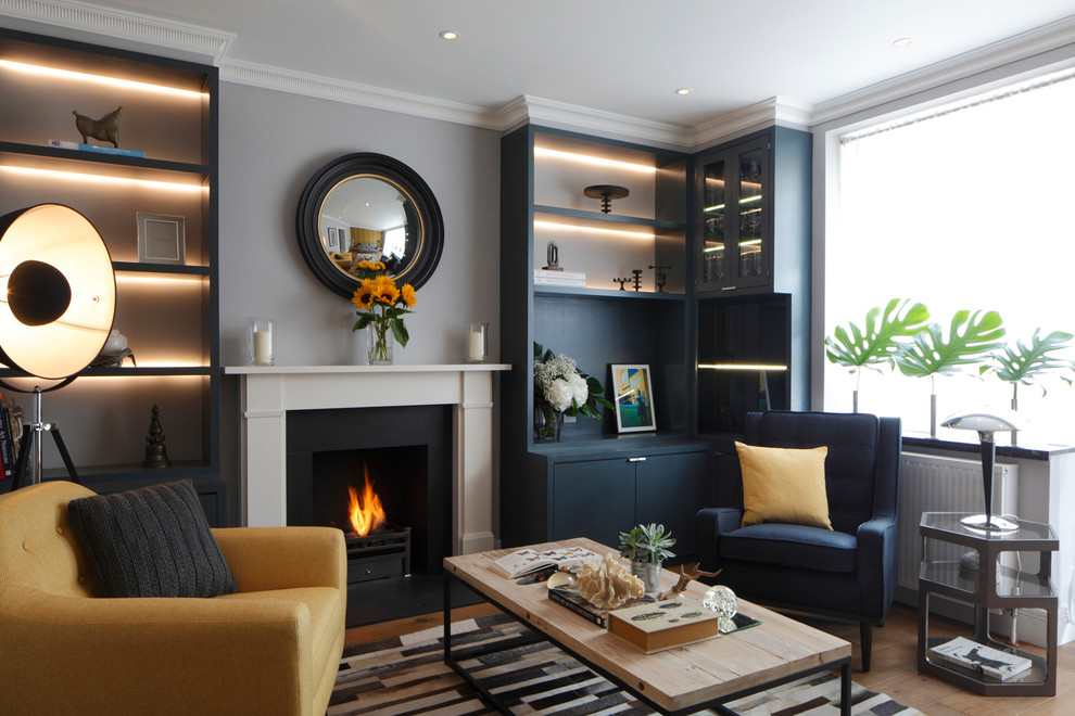 Photo of a small contemporary living room in London with medium hardwood floors, a standard fireplace and brown floor.