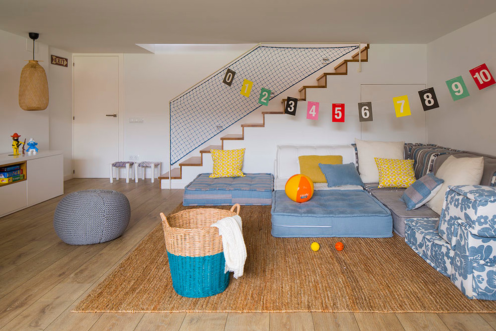 This is an example of a large contemporary gender-neutral kids' playroom for kids 4-10 years old in Other with white walls and medium hardwood floors.