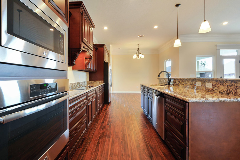 Mid-sized transitional galley medium tone wood floor open concept kitchen photo with an undermount sink, beaded inset cabinets, medium tone wood cabinets, granite countertops, stainless steel appliances and an island