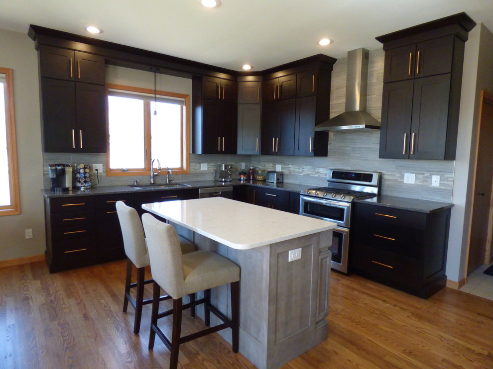 Eat-in kitchen - large transitional l-shaped medium tone wood floor eat-in kitchen idea in Cedar Rapids with an undermount sink, shaker cabinets, dark wood cabinets, quartz countertops, gray backsplash, porcelain backsplash, stainless steel appliances and an island