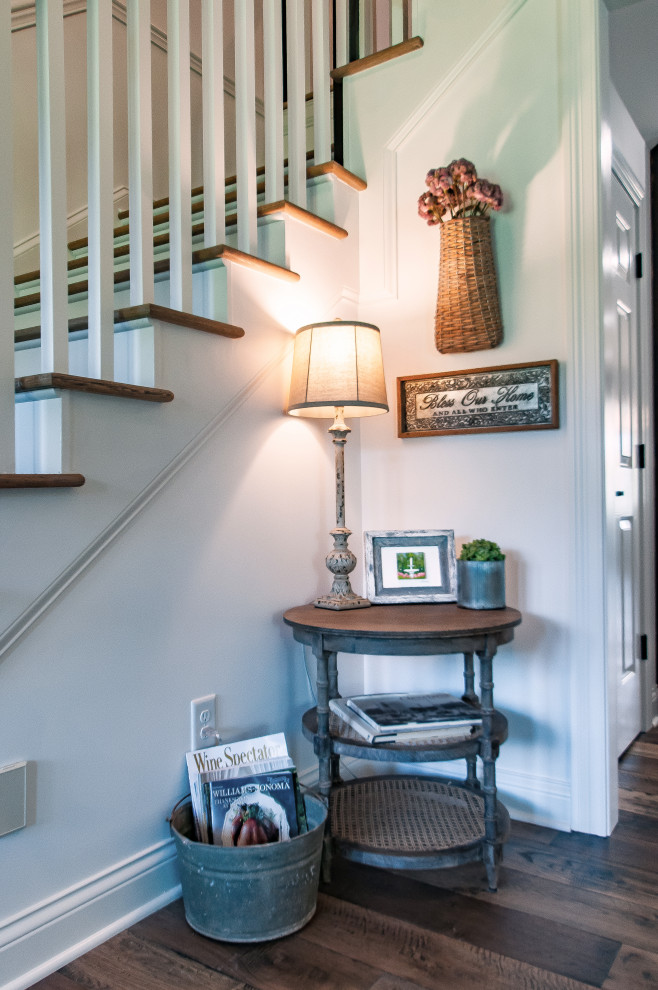 Example of a small cottage medium tone wood floor and brown floor entryway design in Nashville with white walls and a black front door