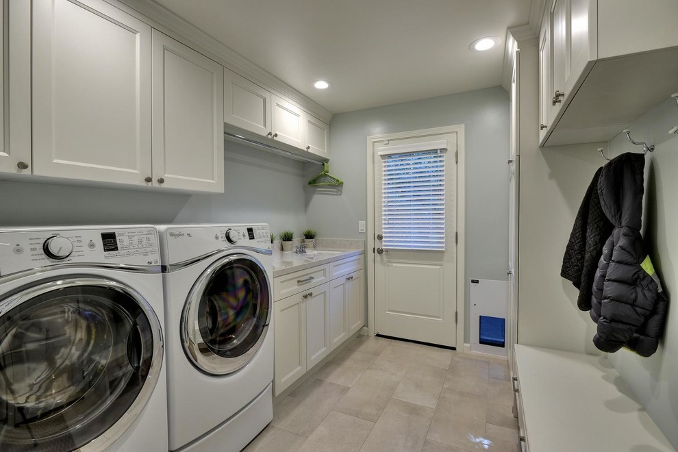 Photo of a mid-sized transitional single-wall utility room in San Francisco with an undermount sink, recessed-panel cabinets, white cabinets, grey walls, porcelain floors, a side-by-side washer and dryer, beige floor and quartz benchtops.