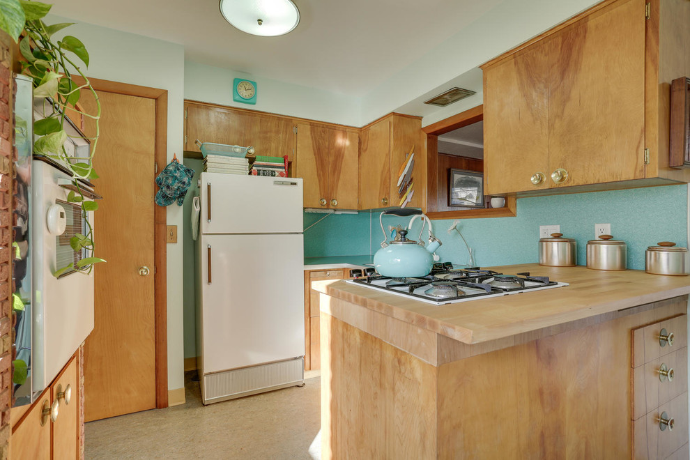 Photo of a mid-sized midcentury u-shaped eat-in kitchen in Portland with a drop-in sink, flat-panel cabinets, light wood cabinets, laminate benchtops, blue splashback, white appliances, linoleum floors, a peninsula and turquoise floor.
