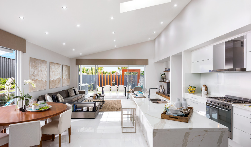 Large contemporary galley open plan kitchen in Newcastle - Maitland with a double-bowl sink, flat-panel cabinets, white cabinets, white splashback, stainless steel appliances, with island, white floor and grey benchtop.