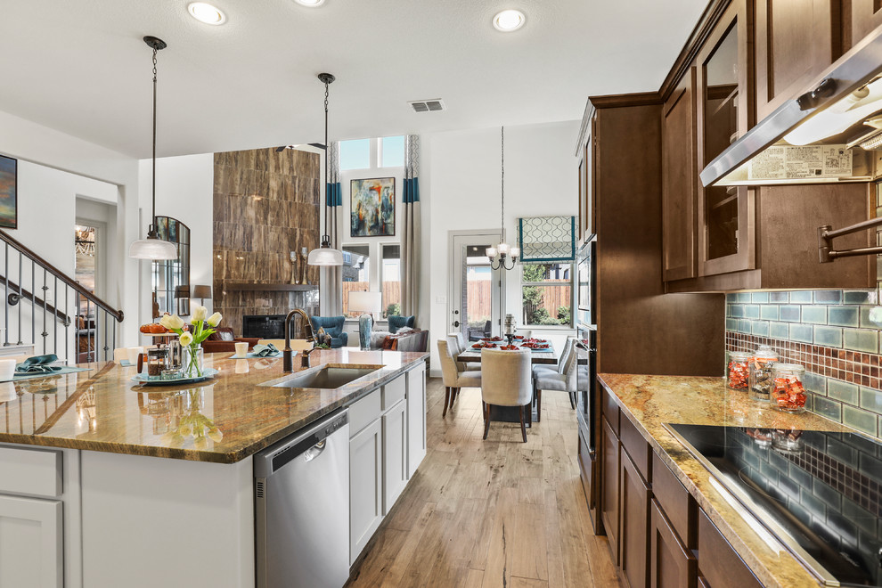 Photo of a large contemporary l-shaped eat-in kitchen in Dallas with an undermount sink, raised-panel cabinets, dark wood cabinets, limestone benchtops, blue splashback, subway tile splashback, stainless steel appliances, medium hardwood floors, with island, brown floor and brown benchtop.