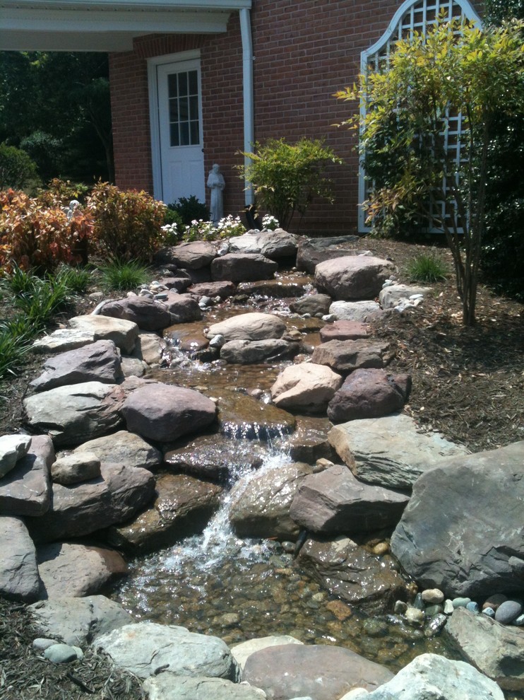 Inspiration for a mid-sized sloped garden in DC Metro with a water feature.
