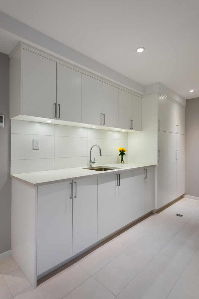 Photo of a mid-sized asian galley utility room in Vancouver with an undermount sink, flat-panel cabinets, white cabinets, quartz benchtops, grey walls, grey floor and black benchtop.