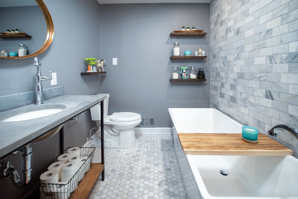 This is an example of a mid-sized transitional 3/4 bathroom in Baltimore with a freestanding tub, a two-piece toilet, gray tile, subway tile, grey walls, ceramic floors, an undermount sink, concrete benchtops, grey floor and grey benchtops.