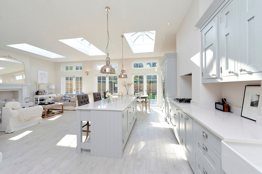 This is an example of a transitional open plan kitchen in London with shaker cabinets, grey cabinets and with island.