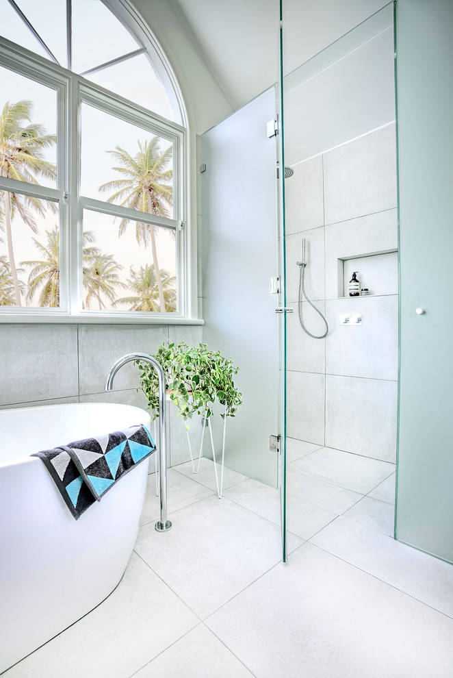Photo of a large contemporary master bathroom in Melbourne with white cabinets, marble benchtops, a freestanding tub, a curbless shower, gray tile and porcelain tile.