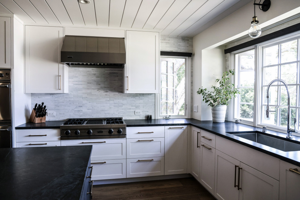 Idéer för stora funkis svart kök, med luckor med profilerade fronter, vita skåp, bänkskiva i täljsten, vitt stänkskydd, stänkskydd i stenkakel, rostfria vitvaror, en köksö och brunt golv