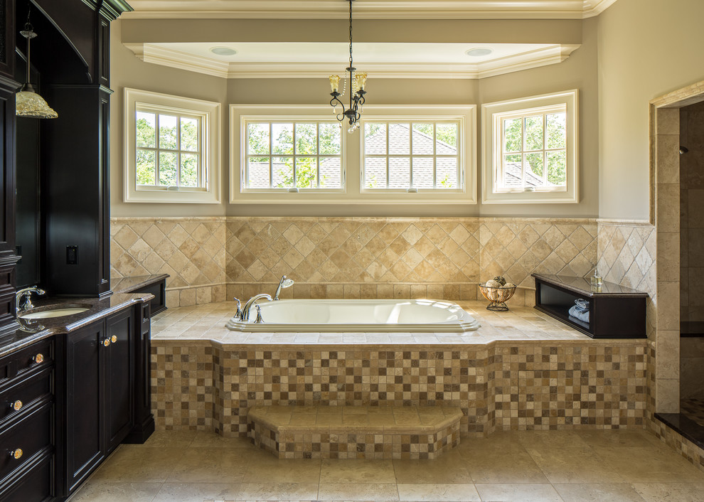 Photo of a traditional master bathroom in New York with shaker cabinets, black cabinets, an alcove tub, beige tile, brown tile, beige walls, an undermount sink and beige floor.