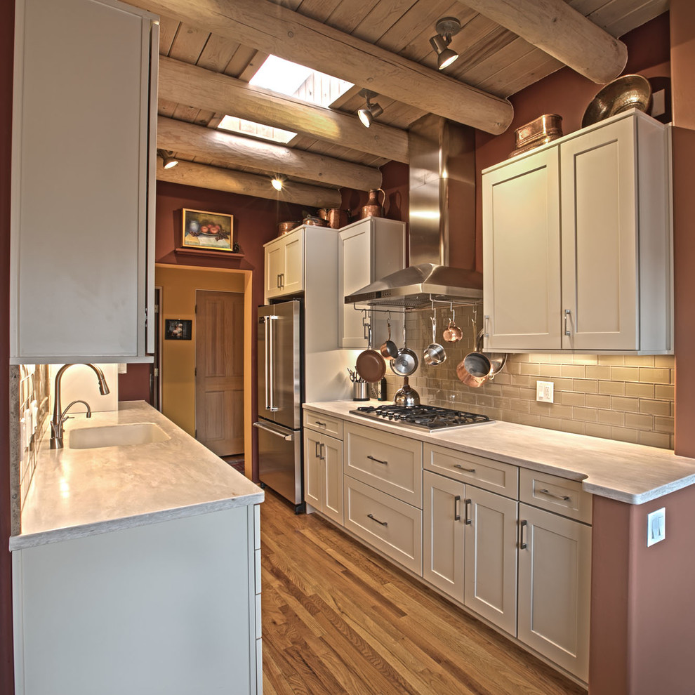 Photo of a small modern galley eat-in kitchen in Albuquerque with a drop-in sink, shaker cabinets, white cabinets, beige splashback, porcelain splashback, stainless steel appliances, medium hardwood floors, no island and brown floor.