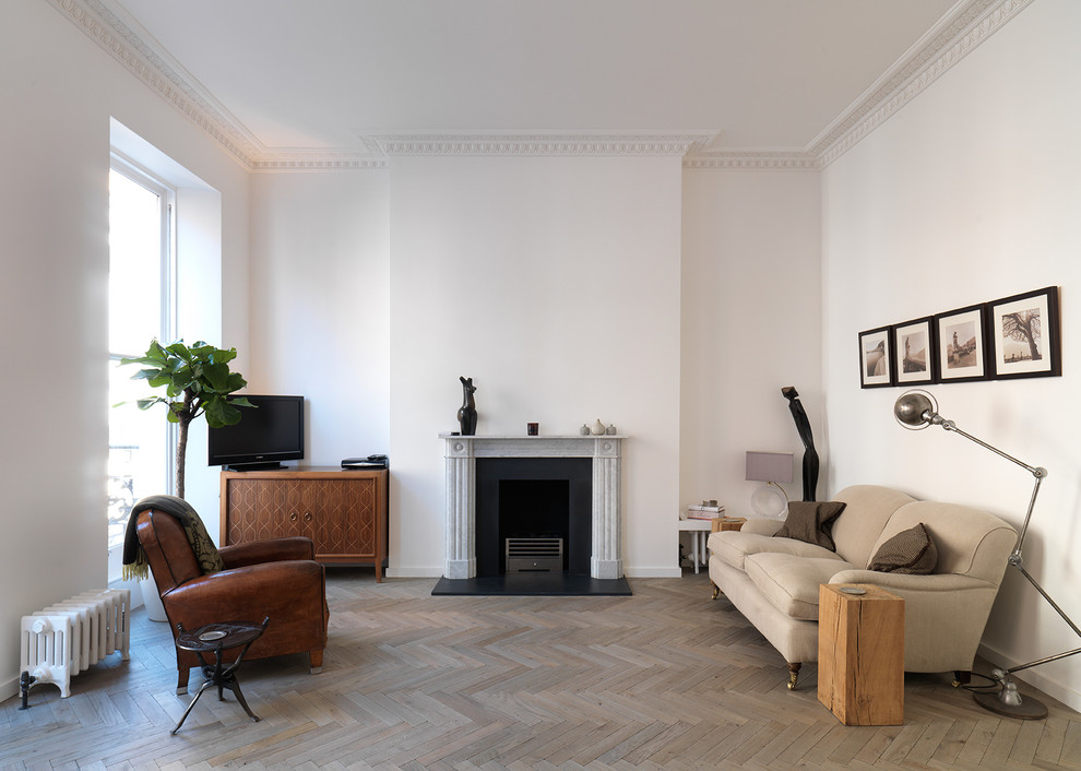 Design ideas for a scandinavian formal living room in London with white walls, light hardwood floors, a standard fireplace and a freestanding tv.