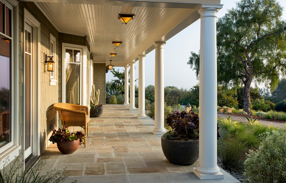Inspiration for a traditional front yard verandah in Santa Barbara with natural stone pavers, a roof extension and a container garden.